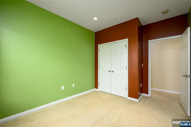 unfurnished bedroom with light carpet and a closet