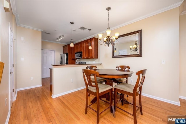 dining space featuring light hardwood / wood-style flooring, ornamental molding, and a chandelier