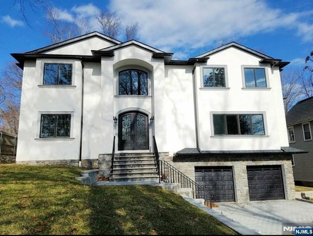 view of front of house with concrete driveway, an attached garage, french doors, a front lawn, and stucco siding