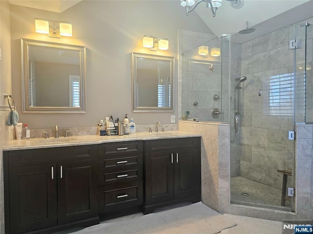 bathroom featuring lofted ceiling, double vanity, a stall shower, and a sink