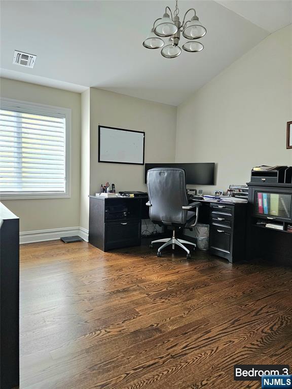 office space featuring dark wood finished floors, visible vents, vaulted ceiling, a chandelier, and baseboards