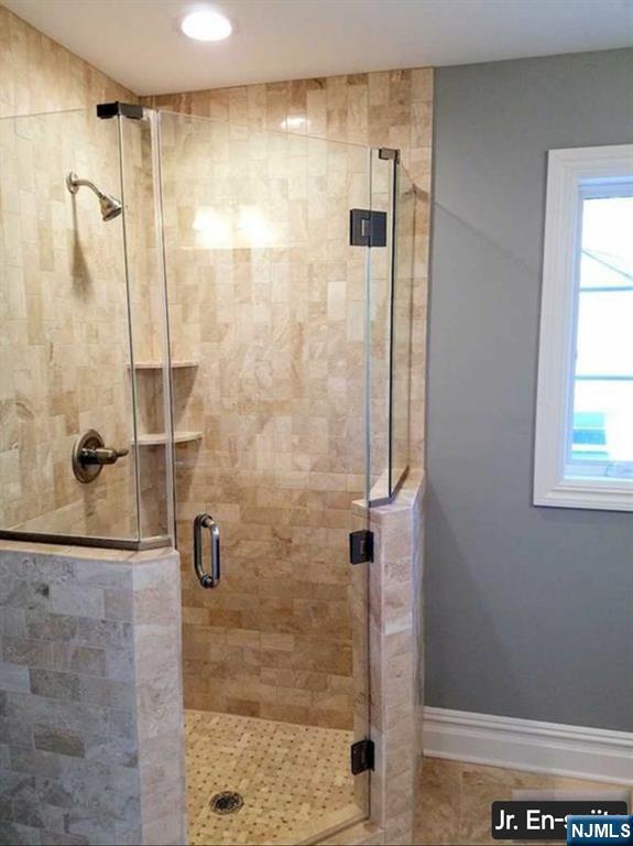 bathroom with a shower stall and baseboards