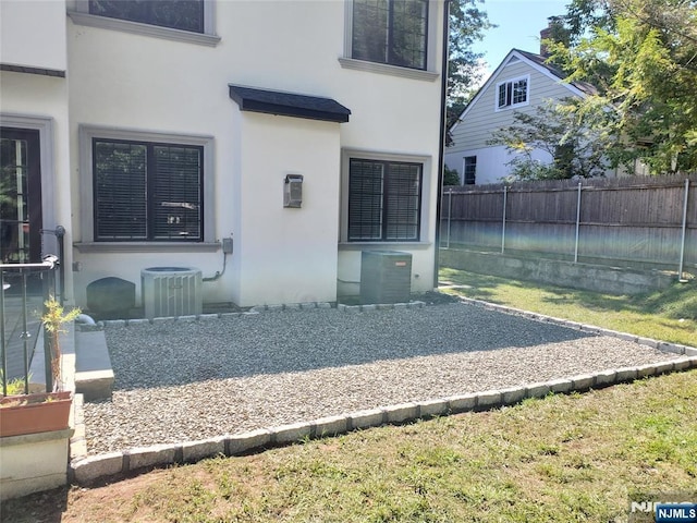 exterior space featuring central AC, fence, and stucco siding