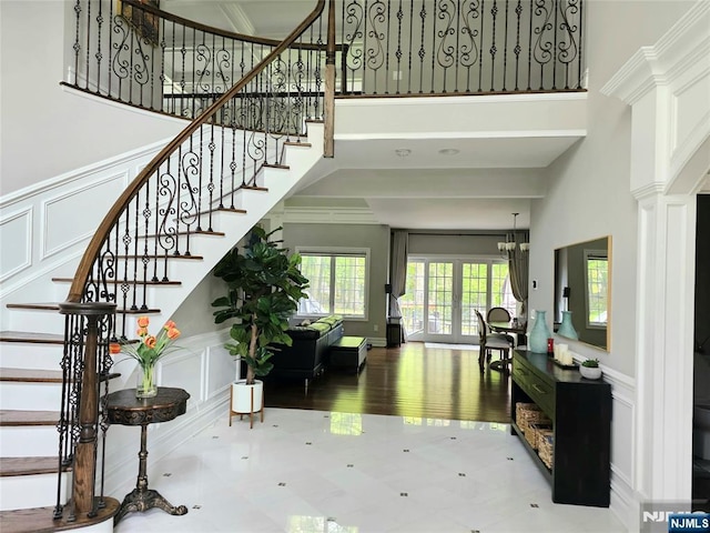 foyer entrance featuring a towering ceiling, ornamental molding, and a decorative wall