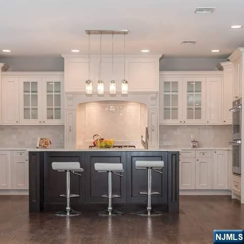 bar featuring double oven, visible vents, hanging light fixtures, and tasteful backsplash