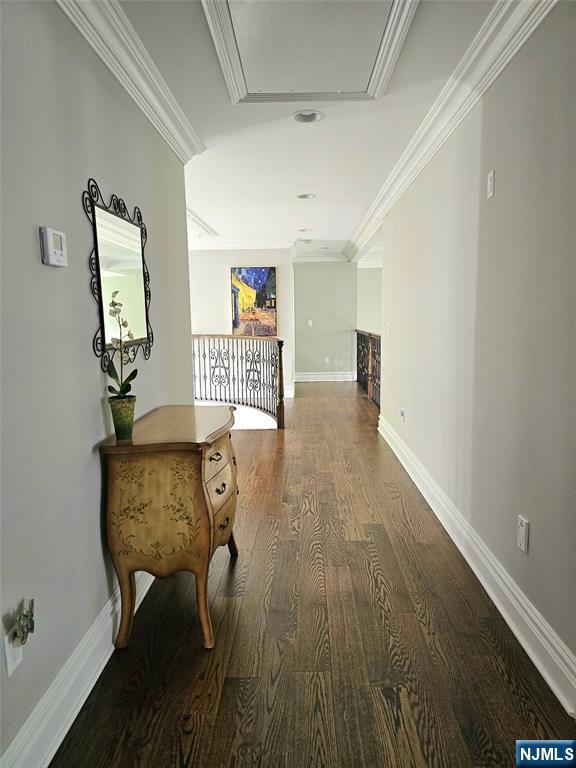 corridor with baseboards, wood finished floors, attic access, and crown molding