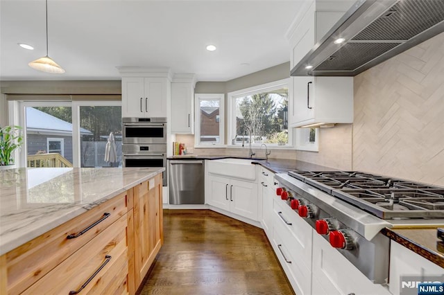 kitchen with white cabinetry, pendant lighting, light stone counters, and wall chimney exhaust hood