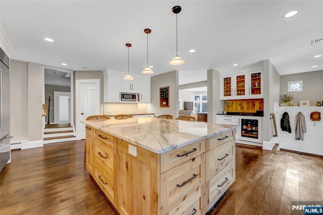 kitchen with pendant lighting, dark wood-type flooring, white cabinetry, a center island, and stainless steel microwave