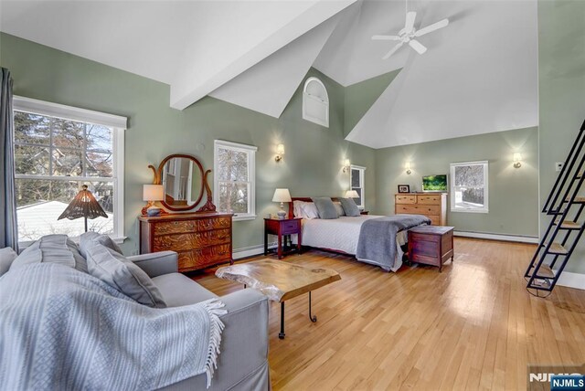 bedroom with beamed ceiling, a baseboard heating unit, ceiling fan, and light hardwood / wood-style flooring