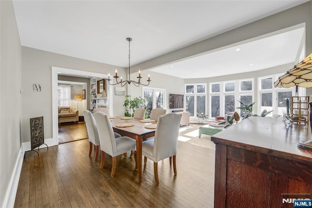 dining area featuring beamed ceiling, hardwood / wood-style floors, and an inviting chandelier