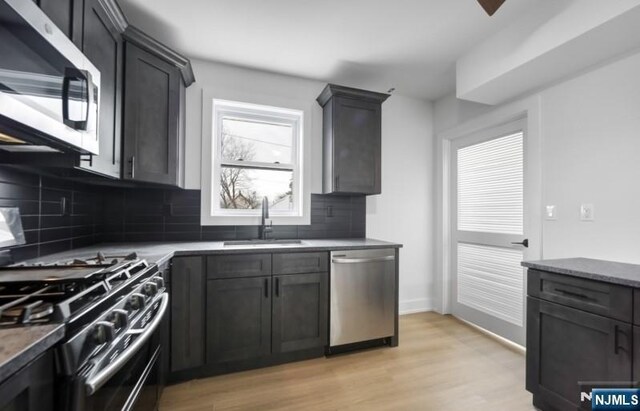 23 Roma St, Nutley, NJ 07110 - kitchen featuring appliances with stainless steel finishes, light wood-type flooring, light stone counters, decorative backsplash, and a sink