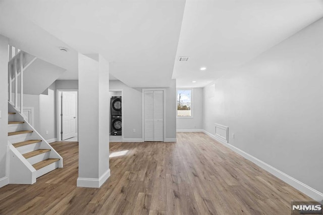 basement with stacked washer and clothes dryer and light hardwood / wood-style floors