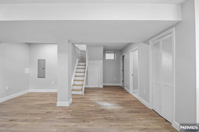 basement with light hardwood / wood-style flooring and electric panel