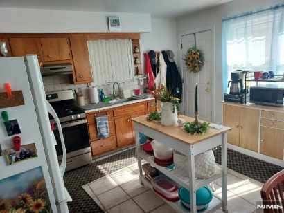 kitchen with sink, stainless steel stove, light tile patterned flooring, and white refrigerator