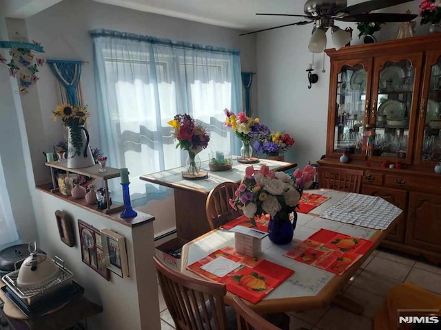 tiled dining room with ceiling fan and baseboard heating