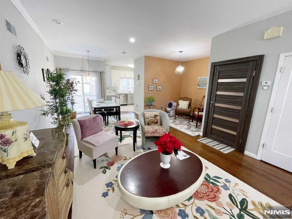 living room featuring hardwood / wood-style flooring, ornamental molding, and an inviting chandelier