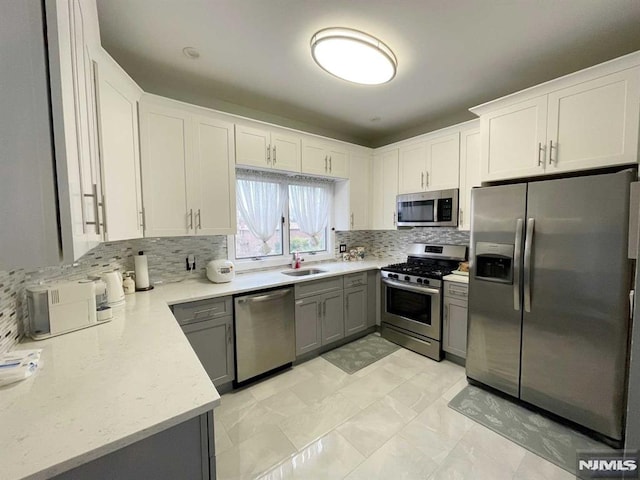 kitchen featuring sink, gray cabinets, stainless steel appliances, tasteful backsplash, and white cabinets