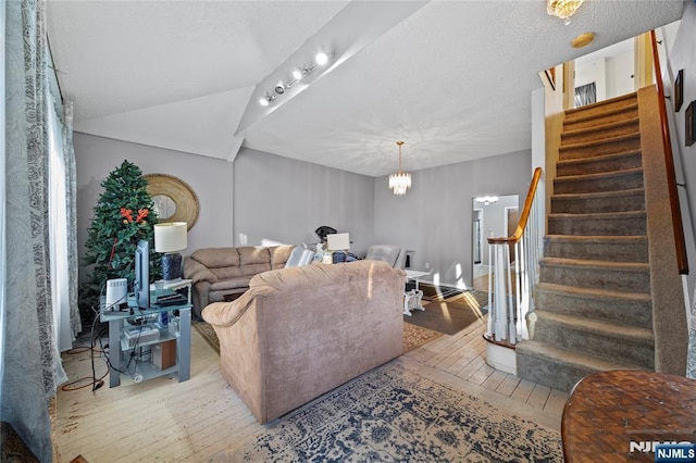 living room with a chandelier, vaulted ceiling, and light hardwood / wood-style flooring