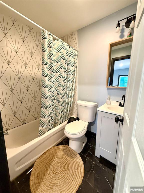 full bathroom with shower / tub combo with curtain, vanity, and toilet