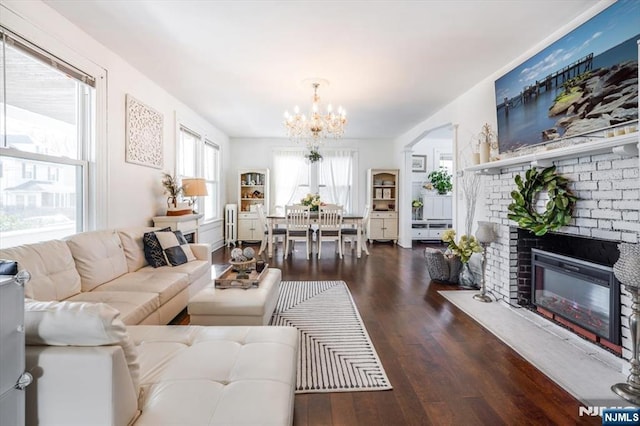 living room featuring a notable chandelier, a fireplace, and dark hardwood / wood-style floors