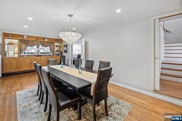 dining space with crown molding, light hardwood / wood-style floors, and a notable chandelier