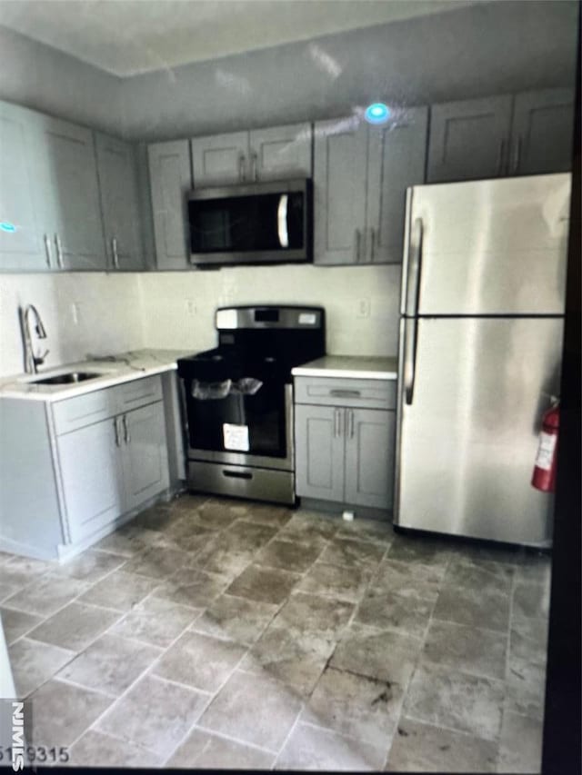 kitchen with gray cabinetry, sink, and stainless steel appliances