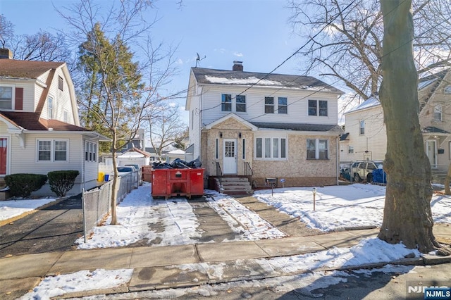 view of front of property with driveway, a chimney, a detached garage, and fence