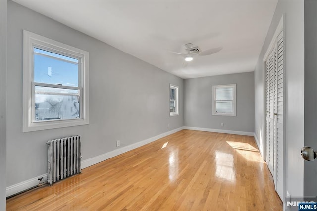 unfurnished bedroom featuring light wood-style floors, radiator, ceiling fan, and baseboards