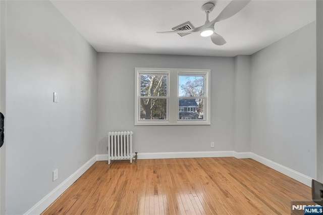 interior space featuring baseboards, radiator heating unit, a ceiling fan, and light wood-style floors