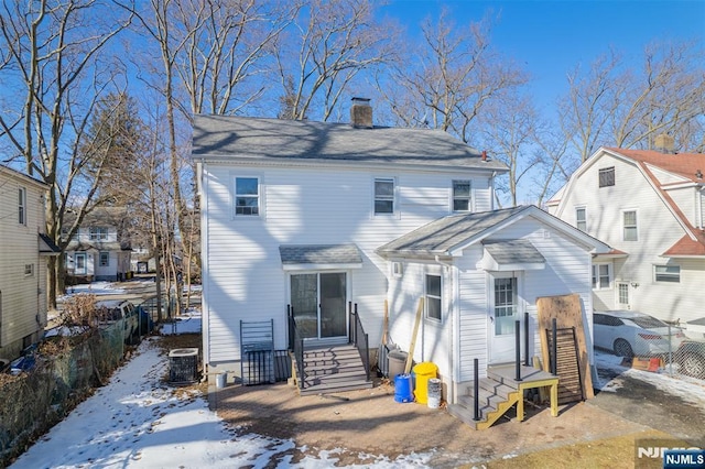 snow covered property featuring entry steps, a chimney, a residential view, fence, and cooling unit