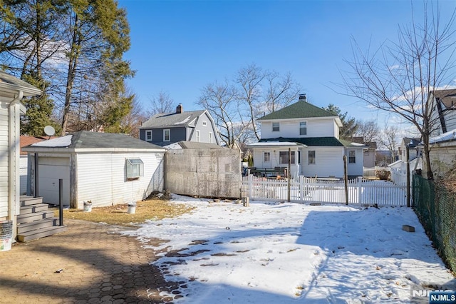 snowy yard featuring an outbuilding, a storage unit, fence private yard, and a residential view