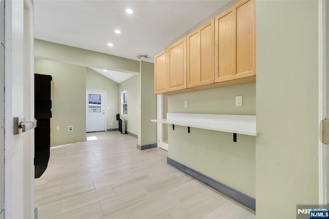 kitchen featuring light brown cabinets, visible vents, vaulted ceiling, and light countertops