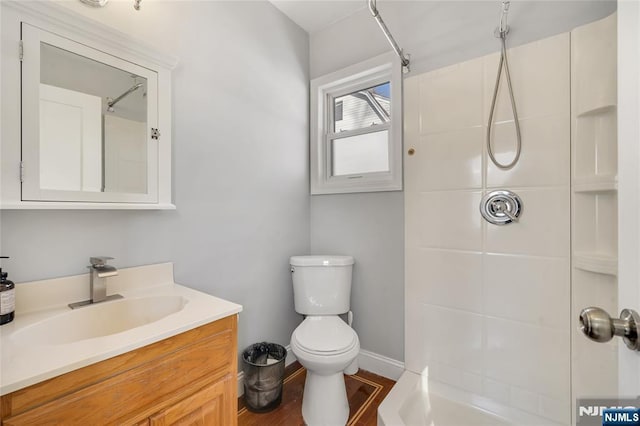 bathroom with walk in shower, vanity, toilet, and baseboards