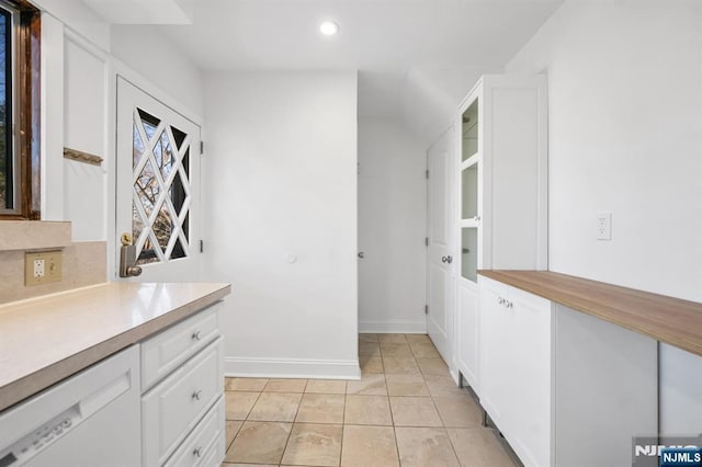 kitchen with light tile patterned floors, tasteful backsplash, and white cabinets