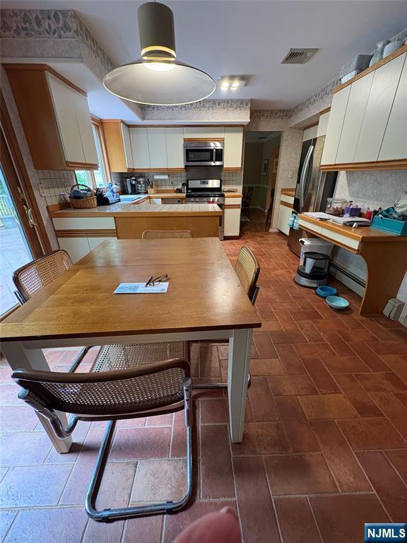 103 Northwood Ave, Demarest, NJ 07627 - kitchen with appliances with stainless steel finishes, decorative backsplash, white cabinets, and a peninsula