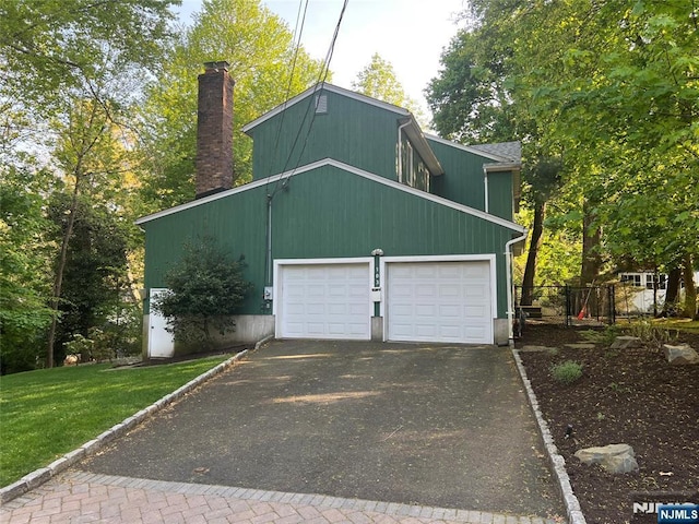 garage featuring fence and aphalt driveway