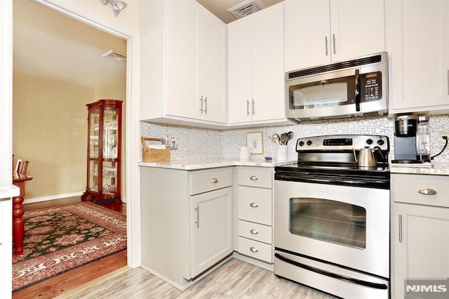 kitchen featuring light stone counters, stainless steel appliances, light hardwood / wood-style floors, decorative backsplash, and white cabinets