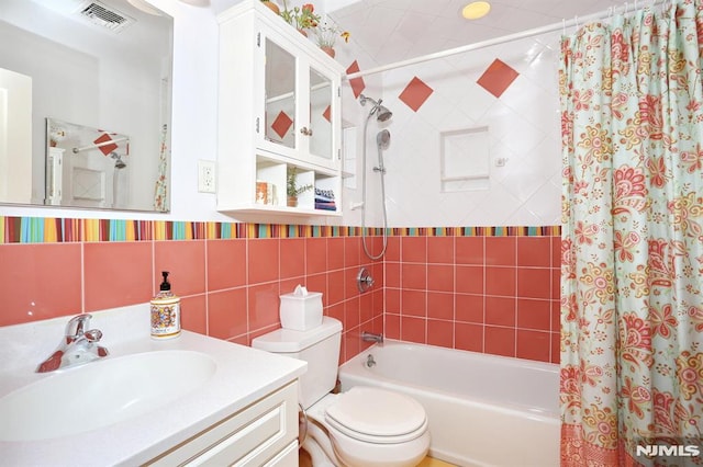 full bathroom with shower / tub combo with curtain, vanity, toilet, and tile walls