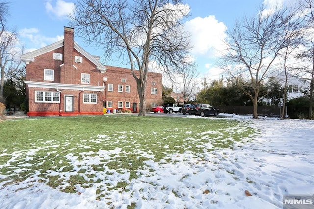 snow covered back of property featuring a yard