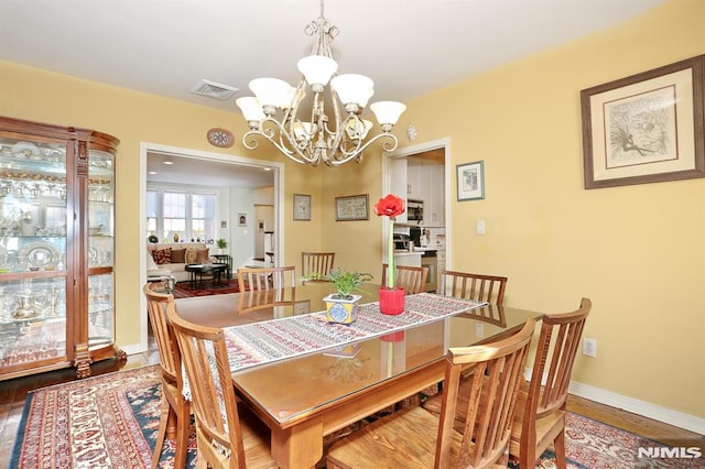 dining room with wood-type flooring and an inviting chandelier