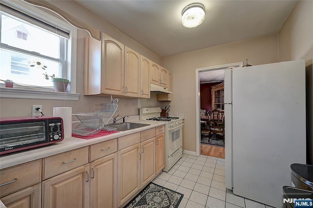 kitchen with light brown cabinetry, sink, white appliances, and light tile patterned floors