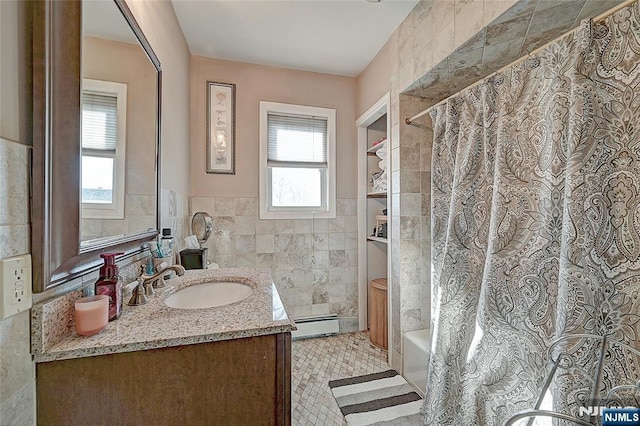 bathroom with tile walls, a baseboard heating unit, vanity, and shower / bath combination with curtain