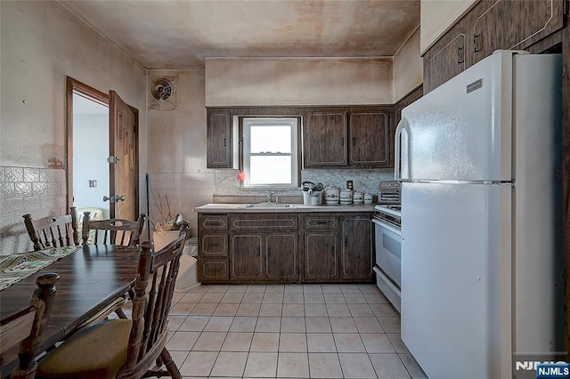 kitchen featuring white appliances, dark brown cabinetry, sink, and light tile patterned floors