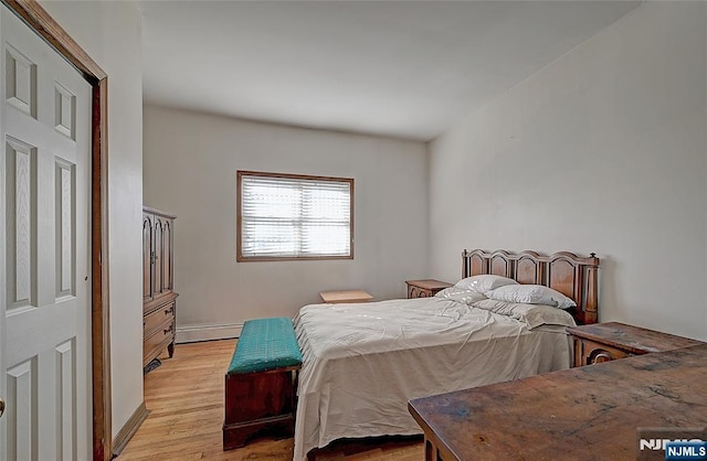 bedroom featuring a baseboard heating unit and light wood-type flooring