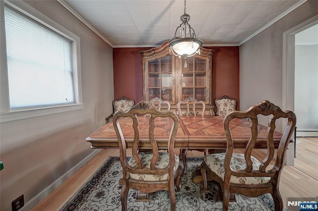 dining space with ornamental molding and light wood-type flooring