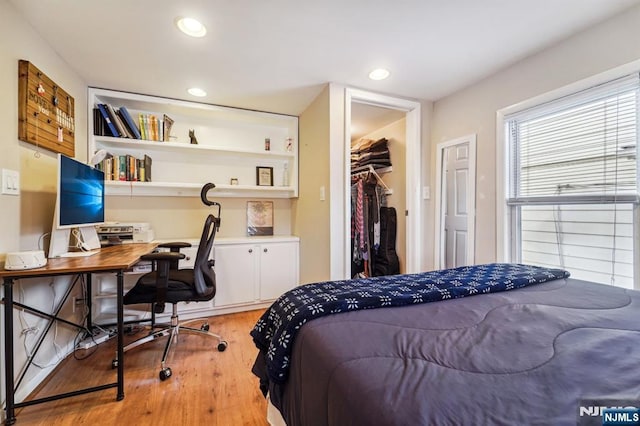 bedroom featuring a walk in closet, a closet, and light wood-type flooring