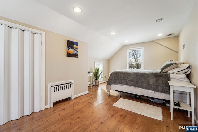 bedroom with lofted ceiling, hardwood / wood-style flooring, and radiator heating unit