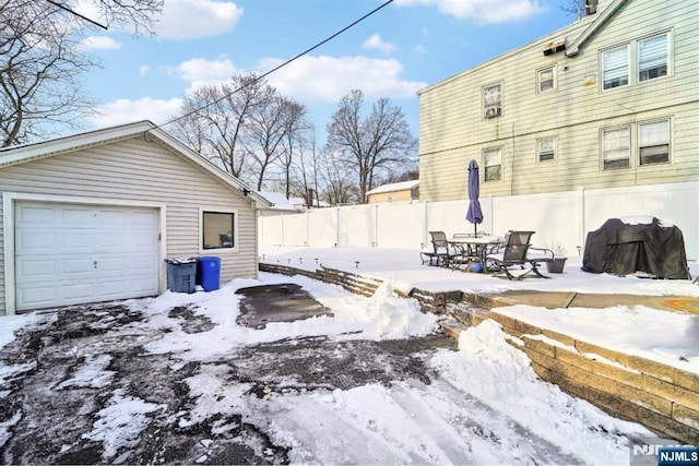 snowy yard featuring a garage and an outdoor structure