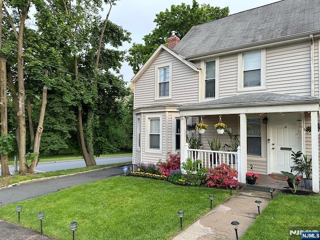 view of front of home featuring covered porch and a front lawn