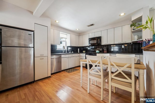 kitchen featuring white cabinetry, appliances with stainless steel finishes, sink, and light hardwood / wood-style flooring